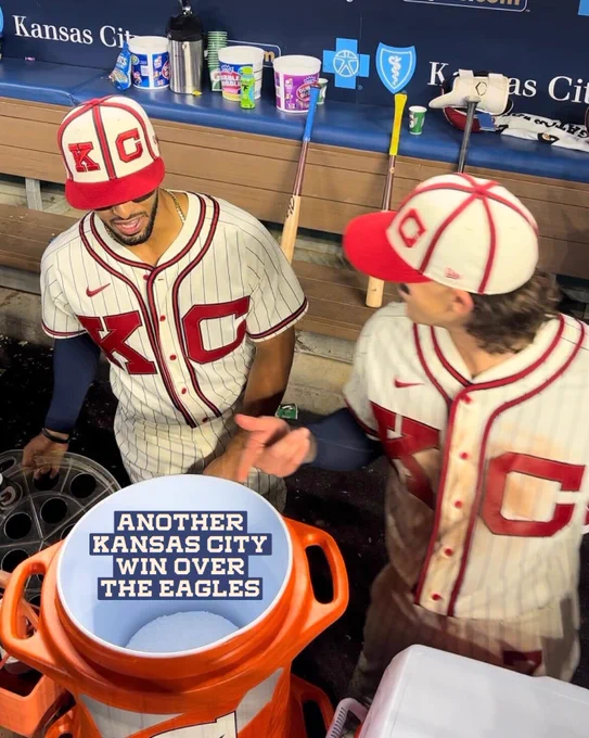 MJ Melendez (left) and Bobby Witt Jr. (right) look into a water cooler in the Royals dugout. Text in the cooler reads, "Another Kansas City win over the Eagles," referencing the win over Houston, who were playing as the Negro League Houston Eagles tonight, and the Kansas City Chiefs win over the Philadelphia Eagles in Super Bowl LVII. 