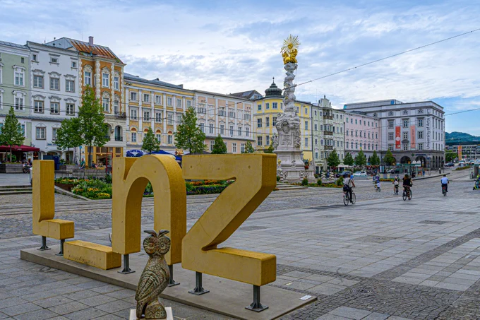 WikiEulen-Skulptur (Replik einer Athener Eule) vor dem Schriftzug „L_nz“ auf dem Linzer Hauptplatz; Isiwal (https://commons.wikimedia.org/wiki/File:Linz_Hauptplatz_mit_WikiEule_2023-4036.jpg), https://creativecommons.org/licenses/by-sa/4.0/legalcode