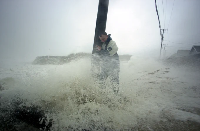 A man clings to a telephone pole as waves crash around him during Hurricane Isabel.