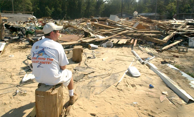A man sits looking out at debris scattered in front of him after Hurricane Isabel.