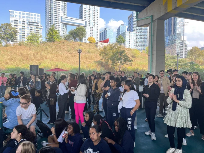 Crowd at staging grounds opening day, looking up to canoe landing park and city place towers in the background