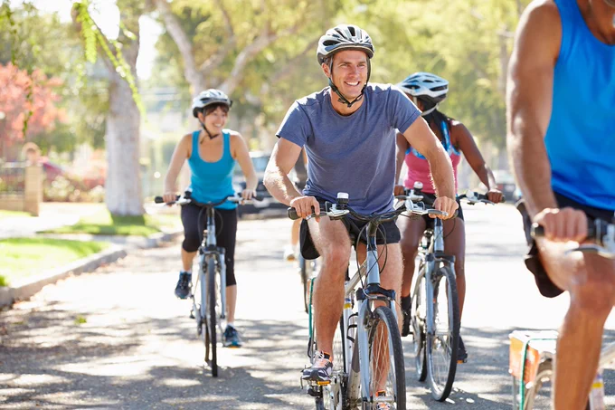 Close up of group of people riding bikes together on road. 