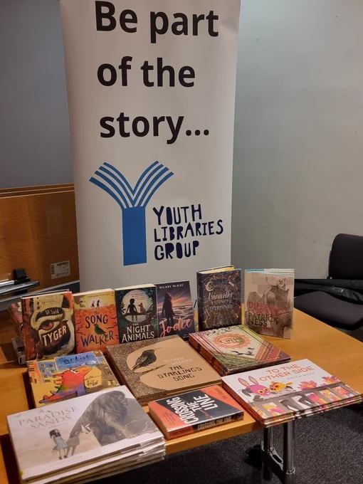 Image shows a table full of books (the regional shortlist) &  YLG banner which says "be part of the story..."