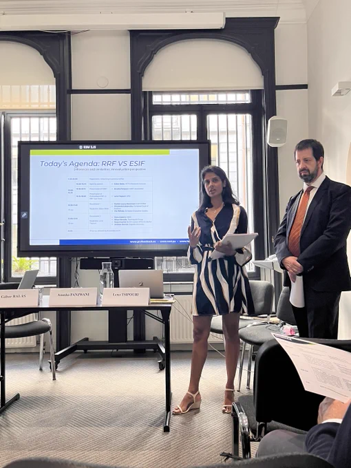 Woman and man standing in front of large screen welcoming participants to a workshop