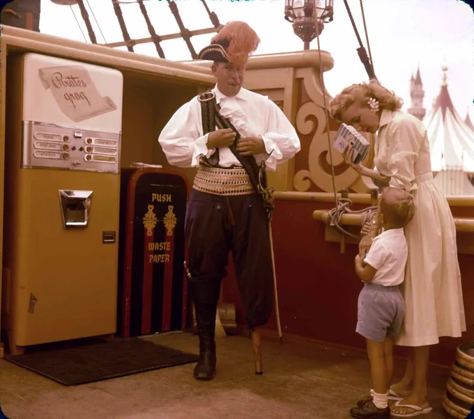 Vintage photo of a cast member dressed as a pirate at Disneyland, standing in front of a trash can