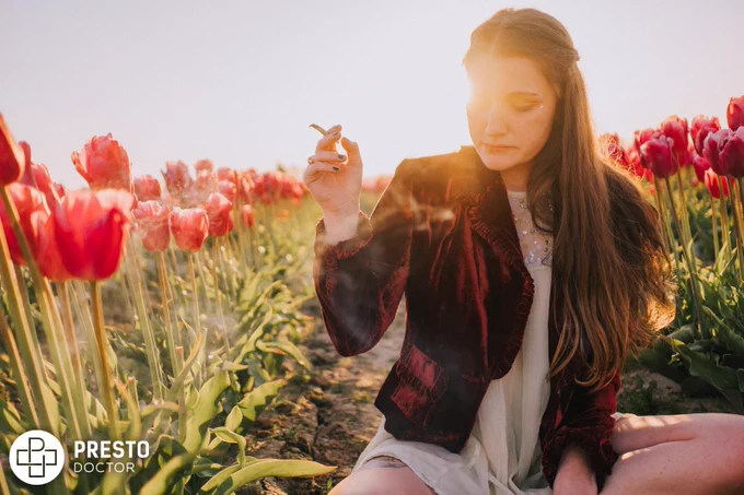 a woman sitting in a field of red tulips, Is Cannabis Linked To Mental Health Issues?