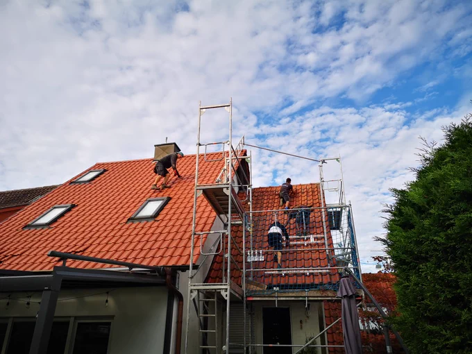 Monteure klettern auf dem Dach um Befestigungen für PV Module zu verschrauben. 