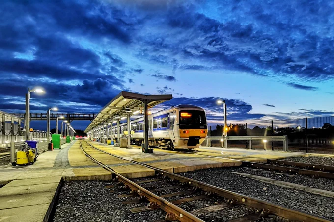 Train on platform over sunset skies