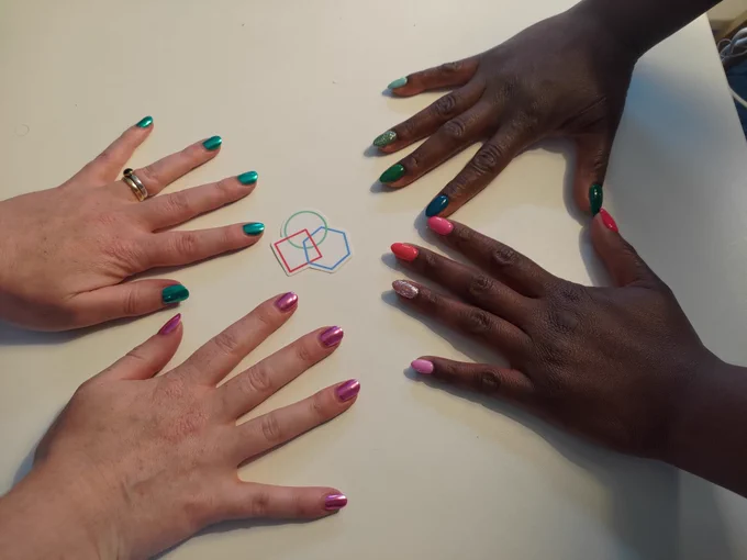 4 hands with turquoise and pink nail varnish arranged on a white table around a codebar sticker