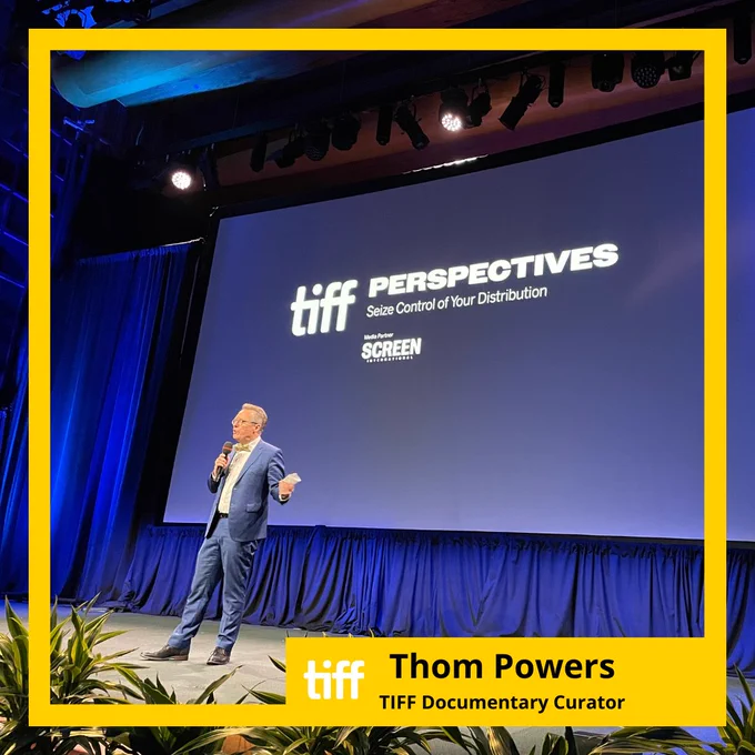 Thom Powers on stage at TIFF speaking into a microphone.