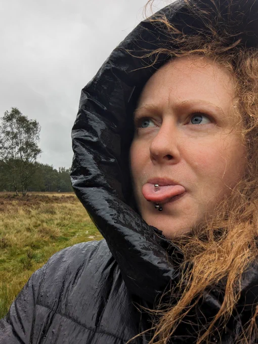 Cherry in a hooded coat. It's clearly raining and she has her tongue out. 