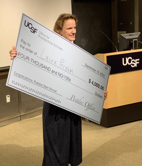 Dr Laura Persson beaming as she holds a HUGE check for $4750 from UCSF!