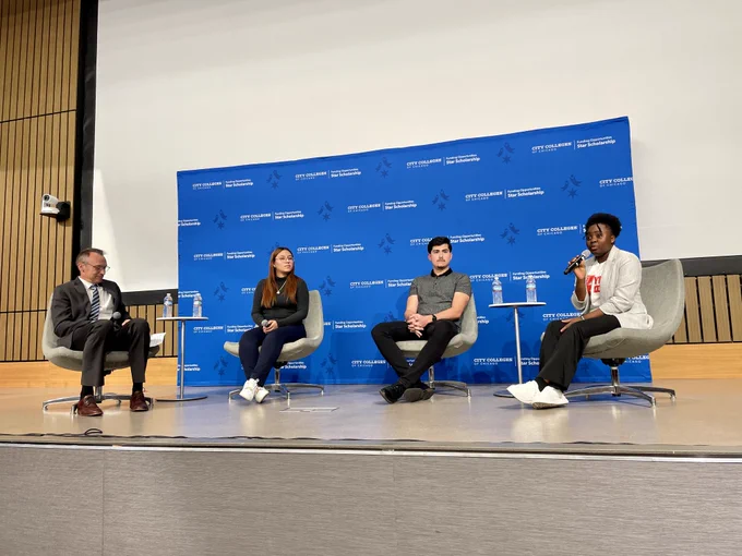 Four individuals sit on stage.