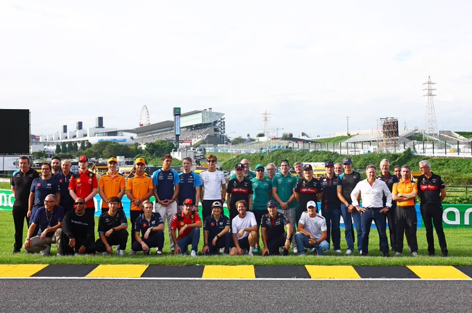 All drivers and team principals line up at Suzuka with Sebastian Vettel and the black and yellow kerb