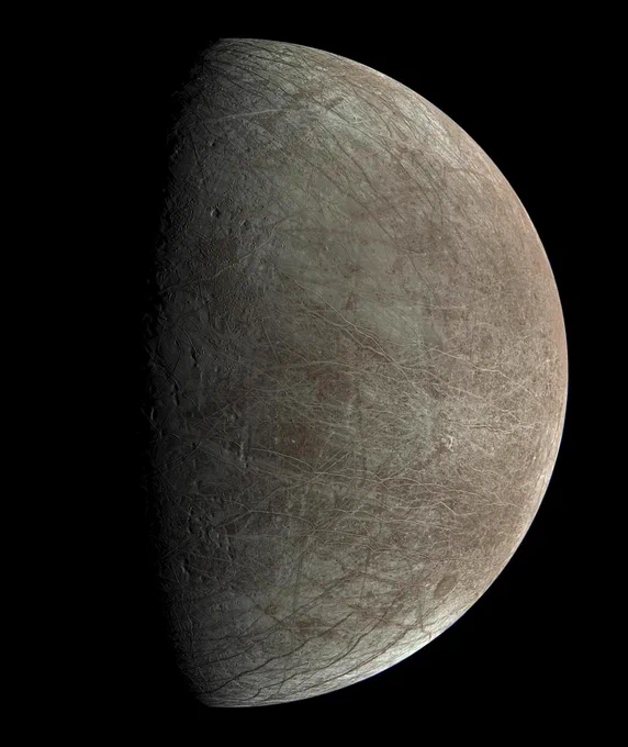 Ridges and bands stretch across Jupiter's icy moon Europa in this view from NASA's Juno spacecraft, revealing the tectonic stresses that the moon has endured over millennia. The day-night boundary is at left. The terrain there is rugged, with pits and troughs. The moon is a dusty beige in color, which contrasts with the dark background of space. Credit: Image data: NASA/JPL-Caltech/SwRI/MSSS Image processing by Björn Jónsson CC BY-NC-SA 2.0
