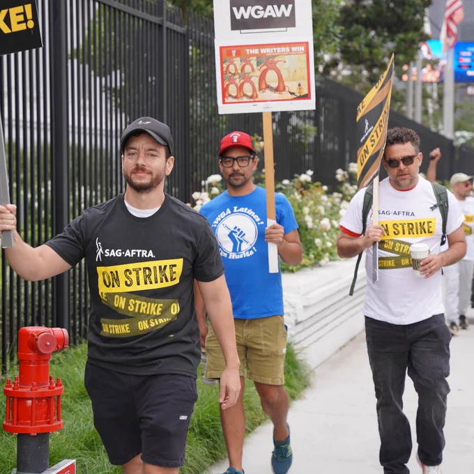 Multiple people on the picket line carrying SAG-AFTRA and WGA on strike signs.
