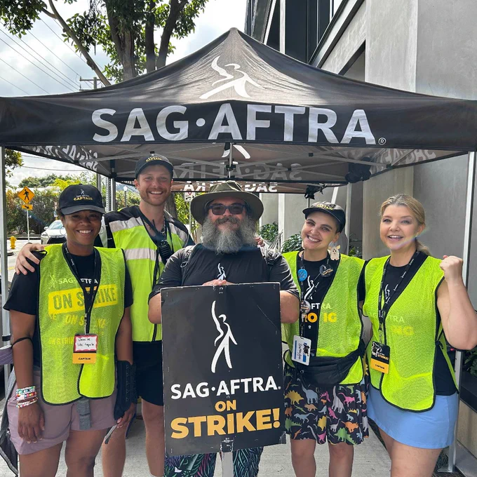 Jack Black holding a SAG-AFTRA ON STRIKE sign with four strike captains, standing in front of the SAG-AFTRA tent.