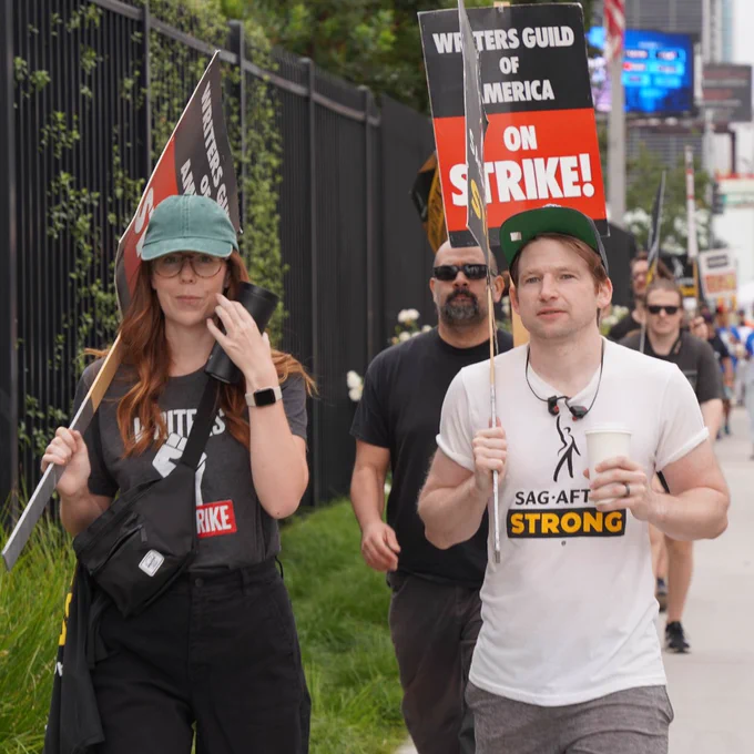 Multiple people on the picket line carrying WGA and SAG-AFTRA on strike signs.
