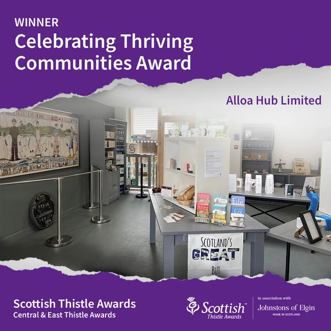 Image of the interior of a room with display tables, desks and shelves with a purple background. Text reads at top Winner Celebrating Thriving Communities Award, Alloa Hub Ltd. Scottish Thistle Awards Central & East Thistle Awards with Scottish Thistle Awards logo. 