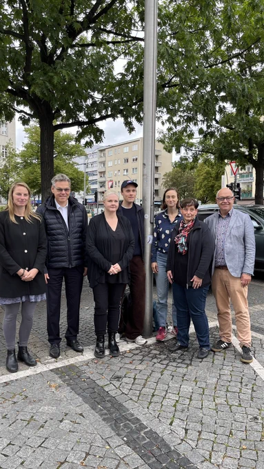 Eine Gruppe aus mehreren Personen steht zusammen und lächelt in die Kamera.