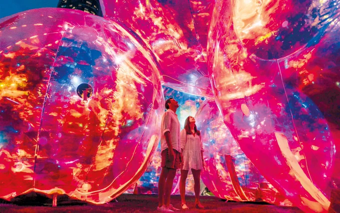 Two people enjoying a light installation called Evanescent, which will be hosted by Leeds Dock and The Royal Armouries, which has been created by Australian design studio Atelier Sisu.