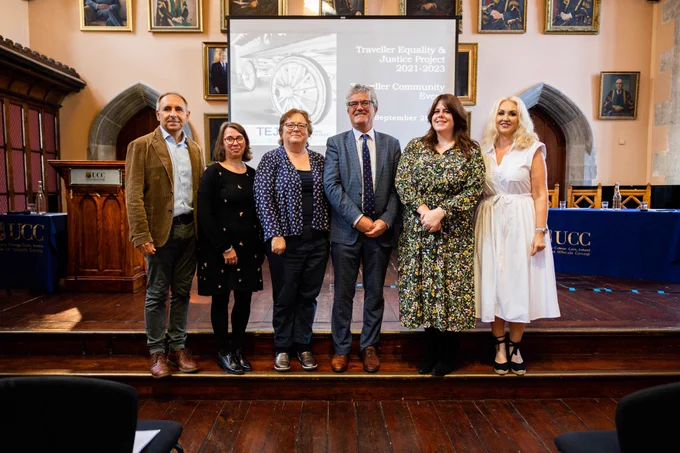 A group of six people stand together in front of screen that says 'Traveller Equality and Justice Project 21 - 23' in the Aula Maxima, UCC. They are Marc Willers KC, Dr Fiona Donson, Eilis Barry, UCC President Professor John O'Halloran, Dr Samantha Morgan Williams and Dr Brigid Quilligan. Image credit: Rubén Tapia/UCC.
