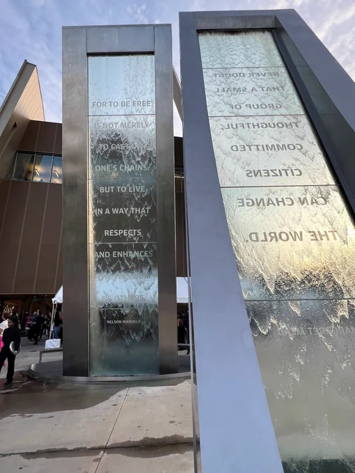 A monument with running water over glass with a quote from Nelson Mandela etched on it. 