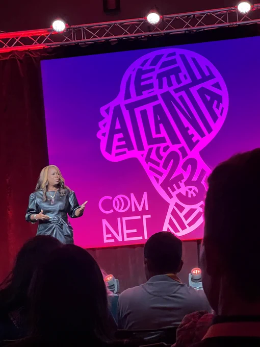 LaTosha Brown, co-founder of Black Voters Matter, on stage with the ComNet23 Atlanta logo on the back wall.
