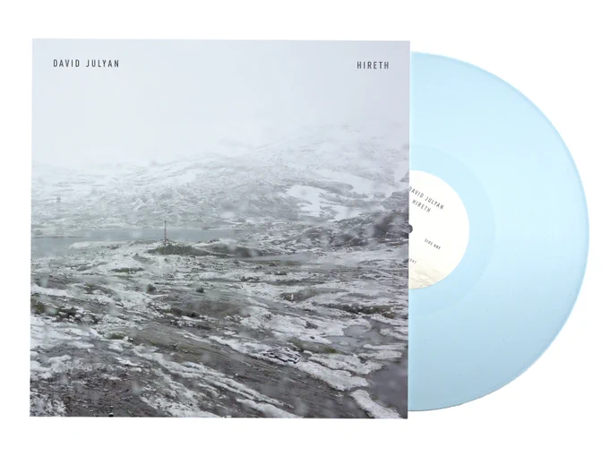 Record cover showing a snow covered landscape with a blue vinyl record half out of the sleeve. 