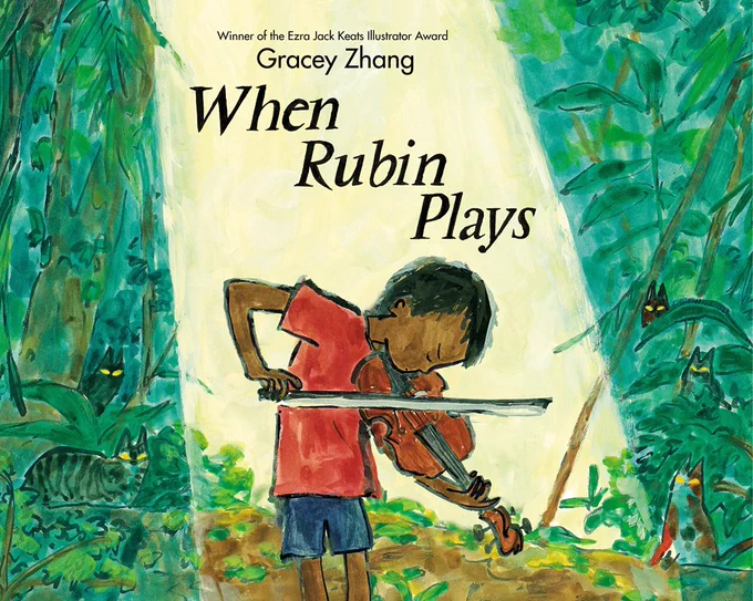 The cover of WHEN RUBIN PLAYS shows a dark-skinned boy playing a violin. There is a spotlight on him, and outside the spotlight is dense green foliage and several cats. The cover art has a painted style. At the top, above the author's name (Gracey Zhang), is the text "Winner of the Ezra Jack Keats Illustrator Award."