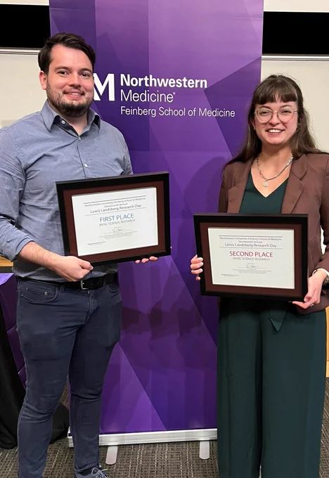 Connor and Maureen stand side-by-side holding their respective awards in front of a purple Northwestern banner. 