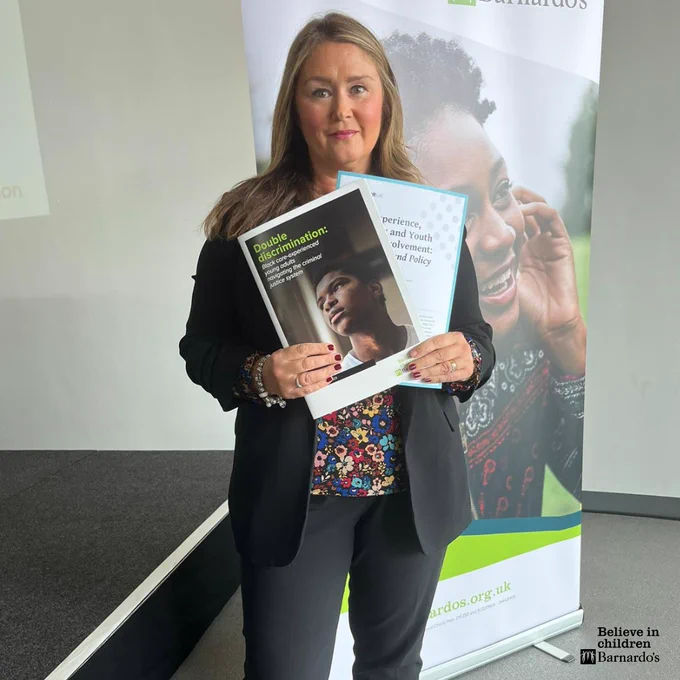 Image shows Barnardo's CEO, Lynn Perry holding a print out of our 'Double Discrimination' report. 