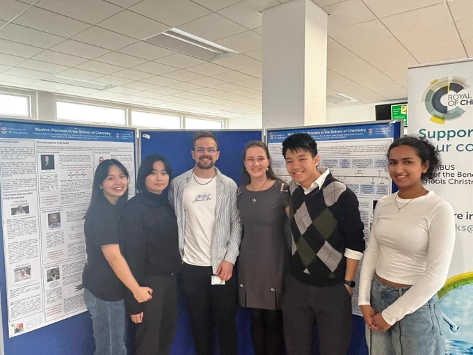A team photograph in front of the displayed poster work from the STEP project