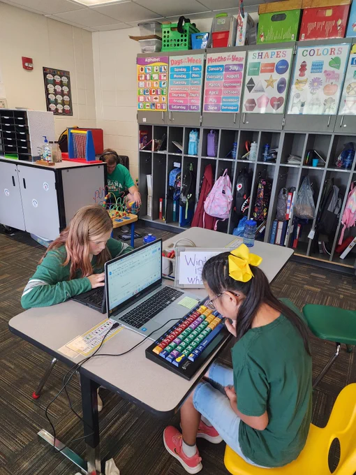 Students using white boards and computers and adapted keyboard to write