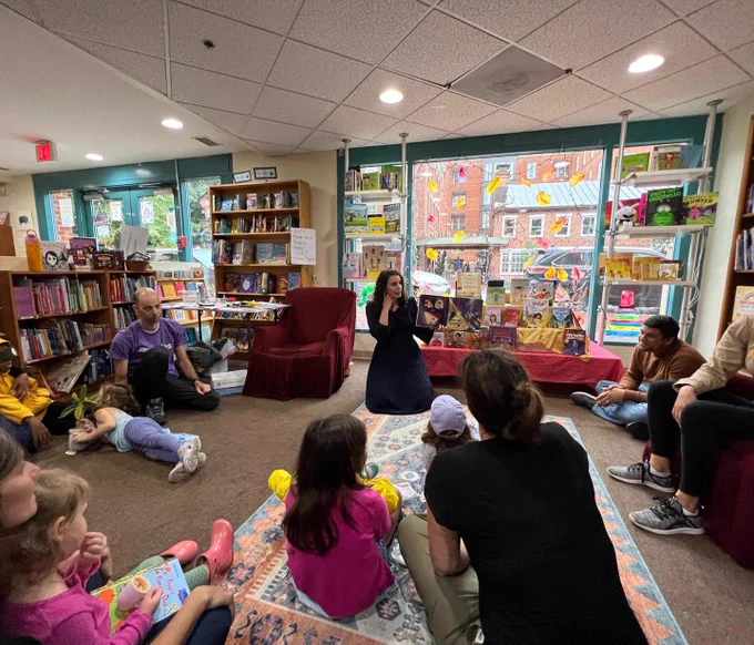 A group of readers on the rug listening to the reading.