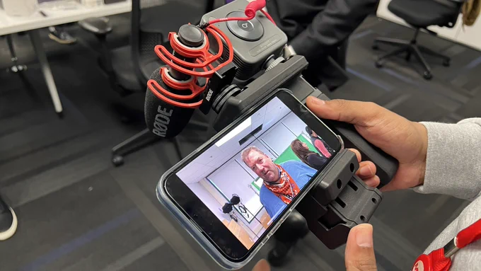A reporter holds a smartphone video rig at a training workshop lead by Robb Montgomery.