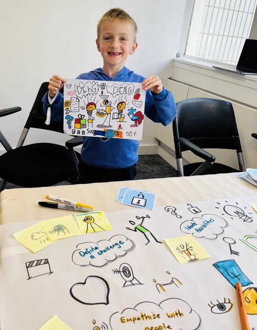 Design club student showing off his finalised poster created using inspiration from bikablo card icons and people with emotions.
