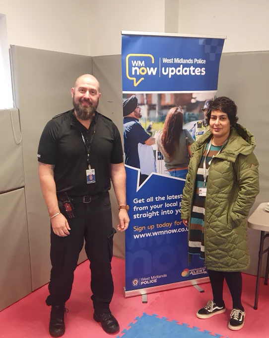 Police and council officers at a domestic abuse awareness raising session at Glebefields Library, Tipton, with a WMnow email updates promotional poster.