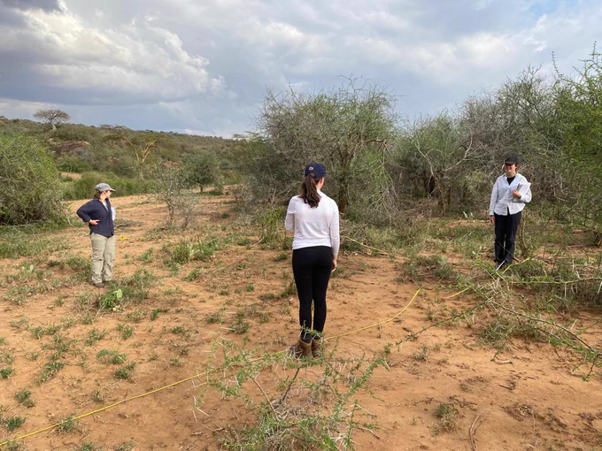 Three female students in the field collecting data for their research projects.
