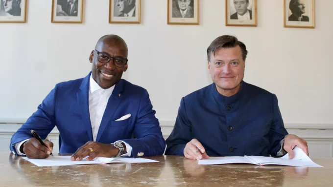 Die Fotografie zeigt Christian Thielemann und Joe Chialo, die einen Vertrag unterzeichnen.