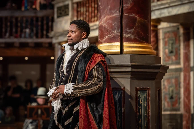 The cast of Twelfth Night: For One Night Only onstage in the Globe Theatre (2023) - one cast member leaning on a pillar looking out into the audience.