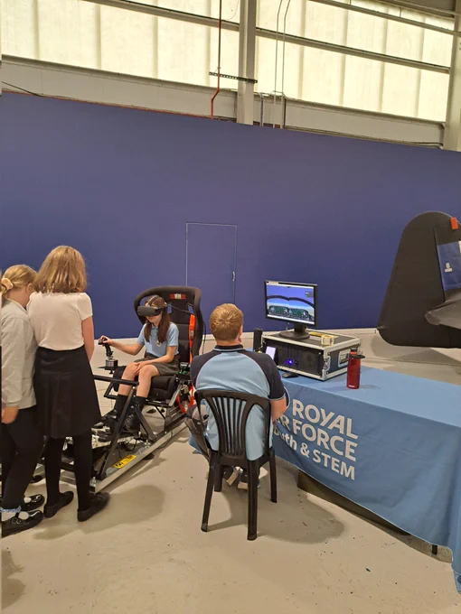 Girl with VR goggles sitting on a chair and steering with a jostick.