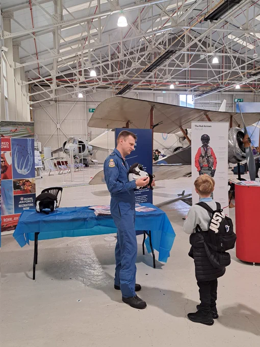 Someone from the Red Arrows team holding a pilot helmet and talking to a young boy.