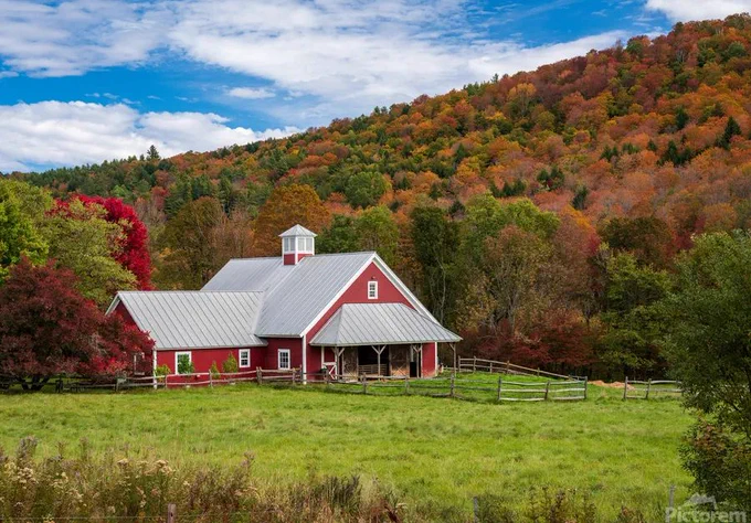 Aerial view of large red farm barn by the side of the road near Barnard in Vermont during the autumn color season