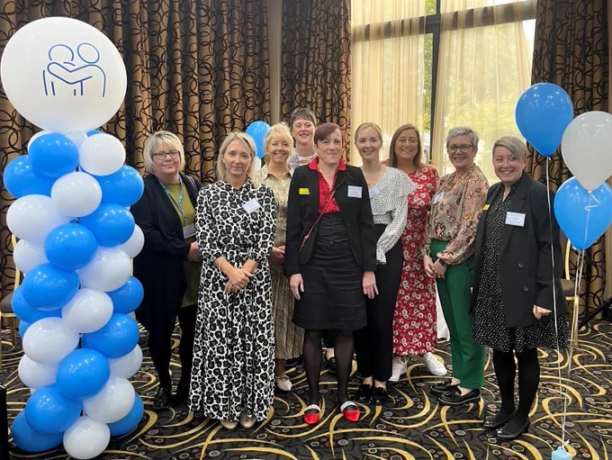 A column of blue and white balloons with a group if women standing at the side of them. 