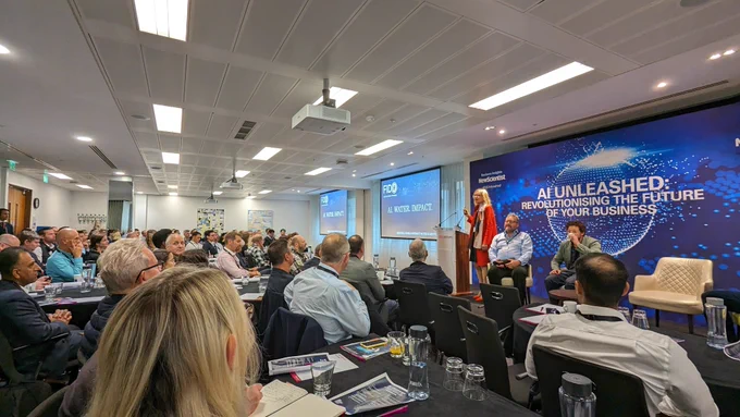 Conference room with people listening to a panel of speakers  on AI Unleashed 