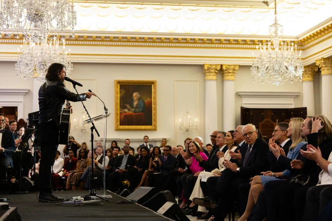 Musician Dave Grohl speaks to and gestures toward a crowd of onlookers at a launch event for the Department of State's Global Music Diplomacy Initiative.