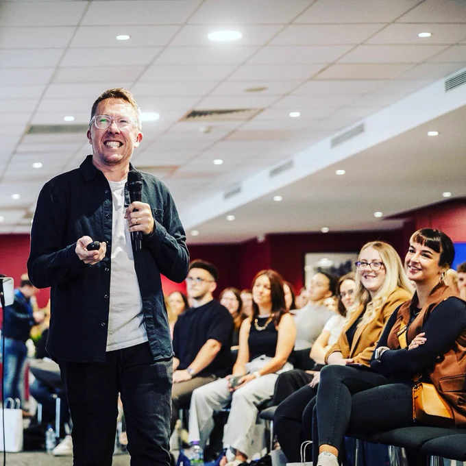 A spectacularly handsome man gives a presentation to 300 smiling, laughing folk.