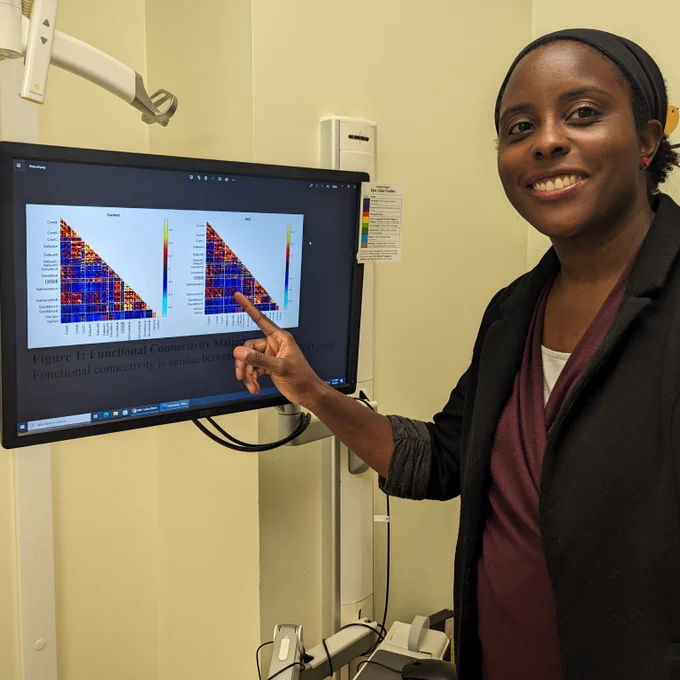 Dr. Eboni Lance smiles at the camera while pointing to research results on a monitor.