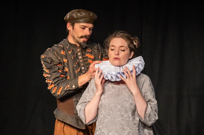 Marlowe putting an Elizabethan ruff around Laura's neck.